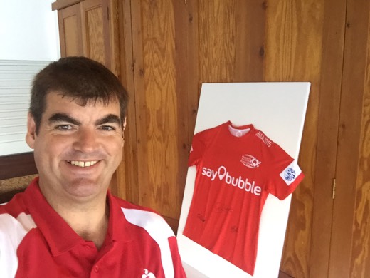 Gary beside the signed red HAA shirt displayed at the celebration.