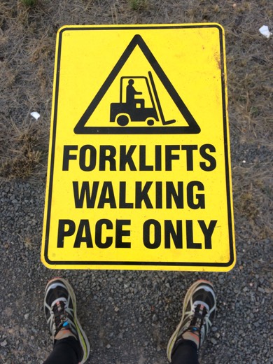 Yellow warning sign reading forklifts walking pace only