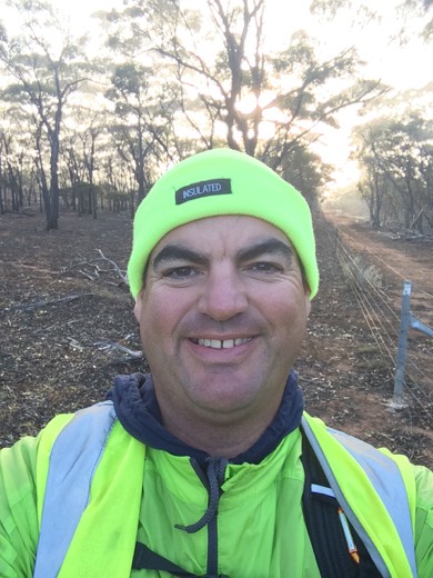 Gary in a bright yellow-green beanie beside the track after sunrise