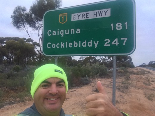 Gary beside an Eyre Highway sign showing Caiguna 181 km and Cocklebiddy 247 km