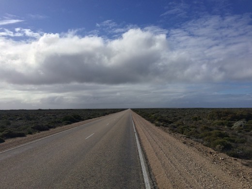 Long straight Eyre Highway under large clouds on the Nullarbor