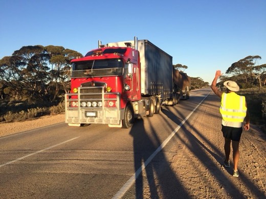 Ols in hi-vis waving to a road train on the Eyre Highway.