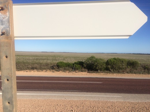 Back of a road sign facing a fenced field