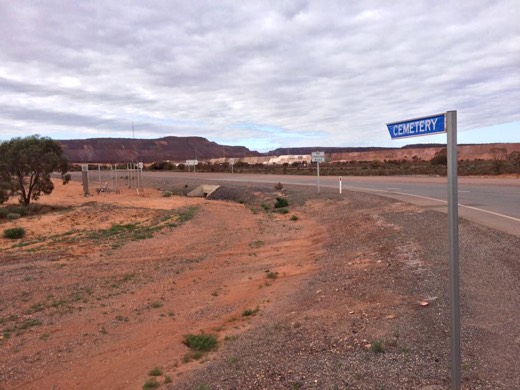 Cemetery sign beside the Eyre Highway with the Iron Knob mine behind it
