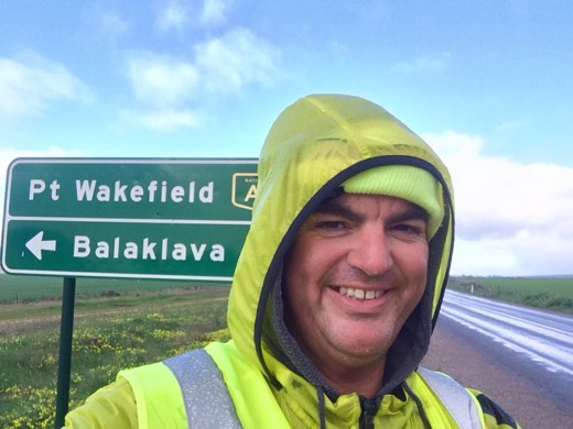 Gary in the yellow beanie beside a Port Wakefield and Balaklava road sign on Day 61