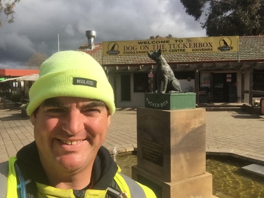 Gary smiling beside the Dog on the Tuckerbox statue near Gundagai.