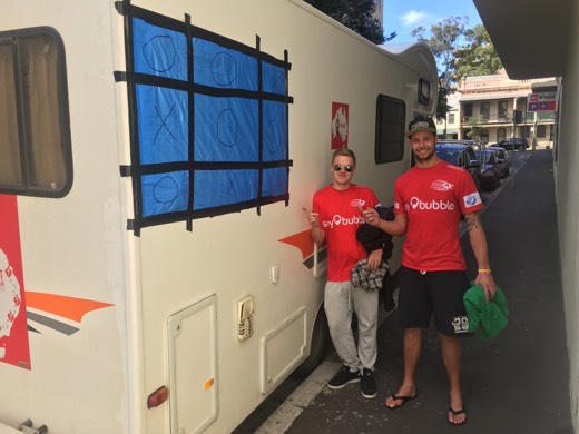 Ben and Ols beside the campervan window repaired with blue tarpaulin, black tape and a noughts-and-crosses design.