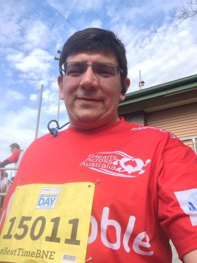 Theunis Koekemoer wearing a red Hearts Across Australia shirt after completing Bridge to Brisbane.