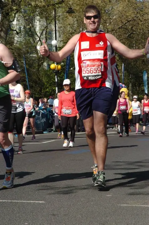 Gary running the 2014 London Marathon with an Australian flag around his shoulders near the final landmarks