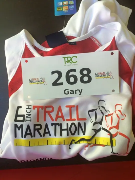 A 6 Inch Trail Marathon race bib and shirt laid out before the event