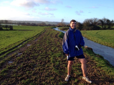 Gary standing by muddy fields and water after running the old school cross-country route.